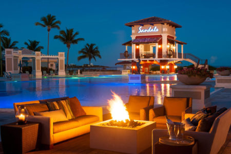 lit fire pits around the main pool at night at sandals emerald bay resort bahamas