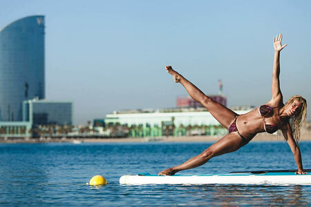 Lady showing pilates and yoga poses against the backdrop of W Barcelona Spain