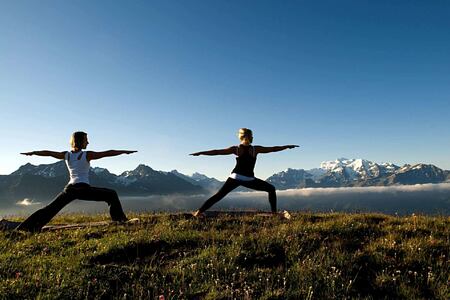 Two people enjoying Yoga with a backdrop of mountains at The Lodge Switzerland