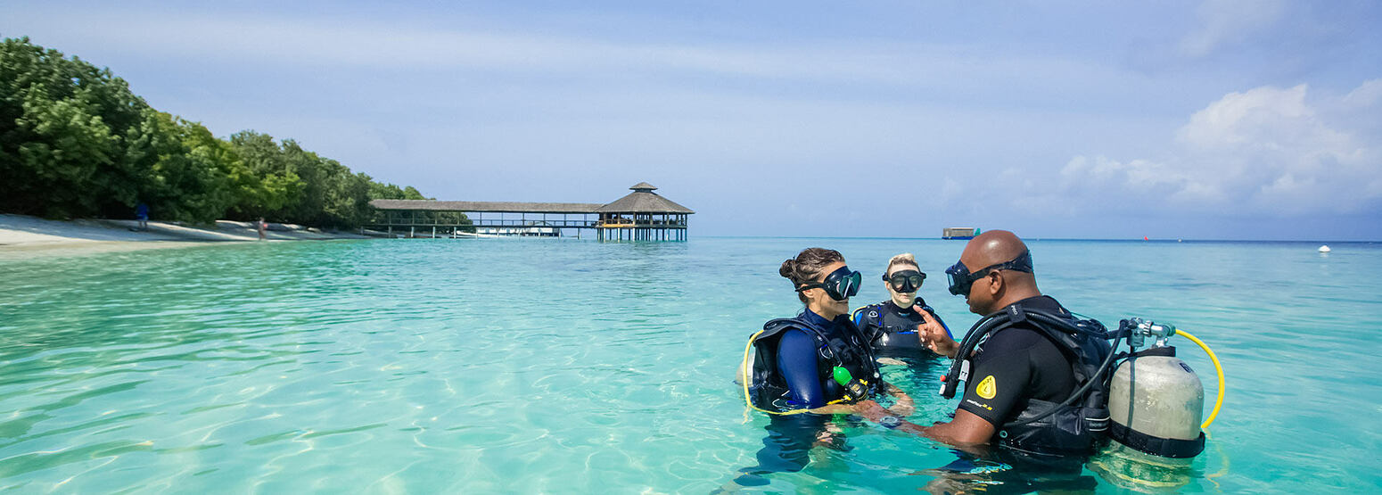 Two people being taught to scuba dive at reethi beach resort maldives
