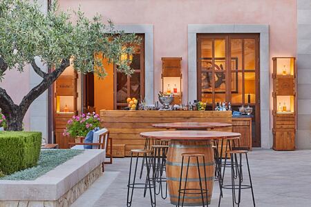 Bar terrace at dusk with barrell dining tables at Ses Oliveres restaurant
