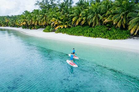 Paddle boarding by the beach Four Seasons Desroches Island Seychelles